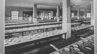 Historic photo of long dining tables set with empty plates